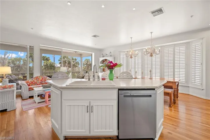 Kitchen with stainless steel dishwasher, a sink, a chandelier, and light wood-style flooring