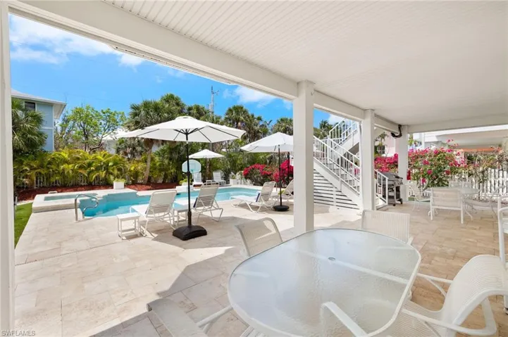 View of patio / terrace with outdoor dining area, stairway, and an outdoor pool
