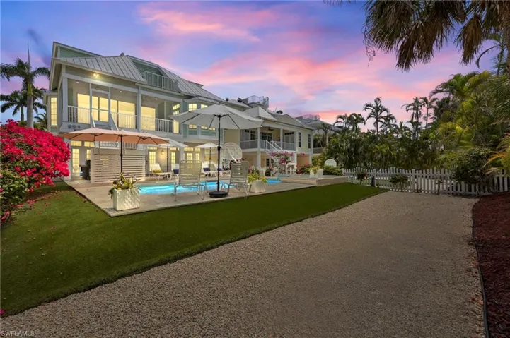 Rear view of property with a sunroom, an outdoor pool, a balcony, and a patio area