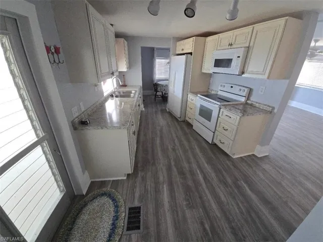 Kitchen with white appliances, a sink, plenty of natural light, and baseboards