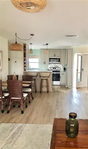Kitchen featuring decorative backsplash, stainless steel appliances, pendant lighting, a kitchen bar, and light wood-type flooring