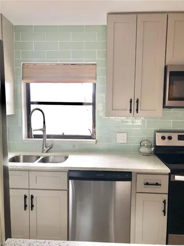 Kitchen with stainless steel appliances, light stone counters, and decorative backsplash