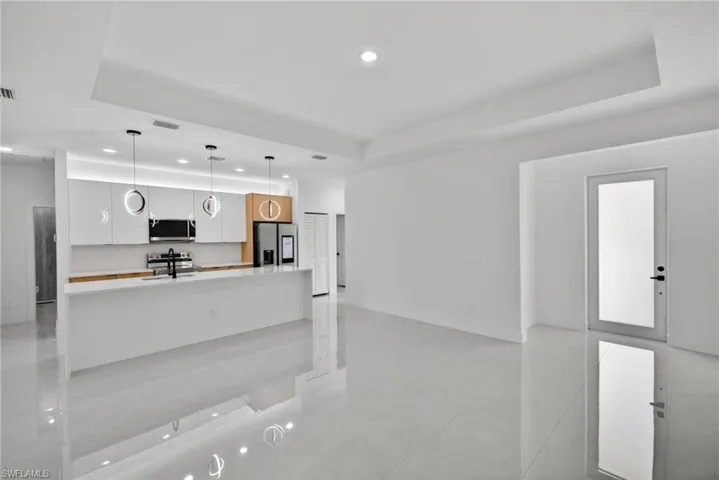 Kitchen with pendant lighting, recessed lighting, white cabinetry, a tray ceiling, and open floor plan