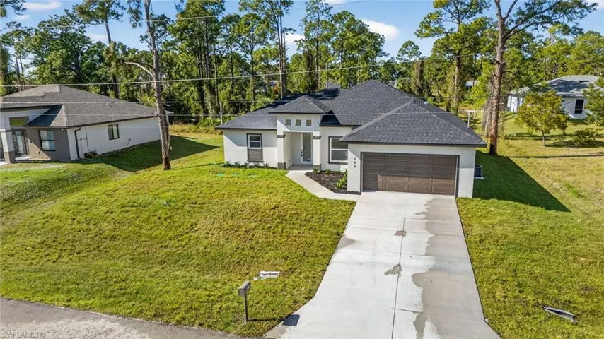 Prairie-style house with stucco siding, driveway, a front lawn, and roof with shingles