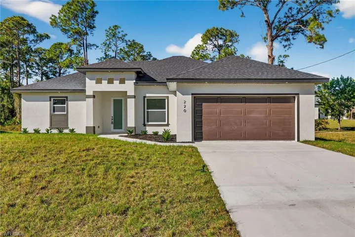 Prairie-style home featuring a front yard, stucco siding, driveway, a garage, and a shingled roof