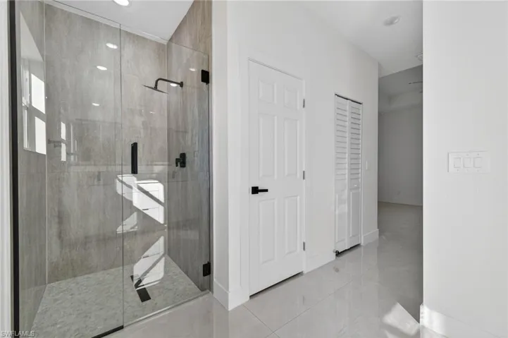 Bathroom with a shower stall and a closet