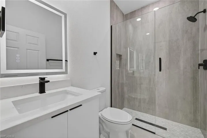 Full bath with vanity, a shower stall, and a textured wall