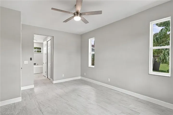 Interior room featuring neutral-toned walls, tile flooring, a multi-blade ceiling fan with integrated lighting, and dual windows