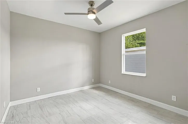 Interior room featuring neutral wall paint, wood-finish tile flooring, and a modern ceiling fan with integrated lighting
