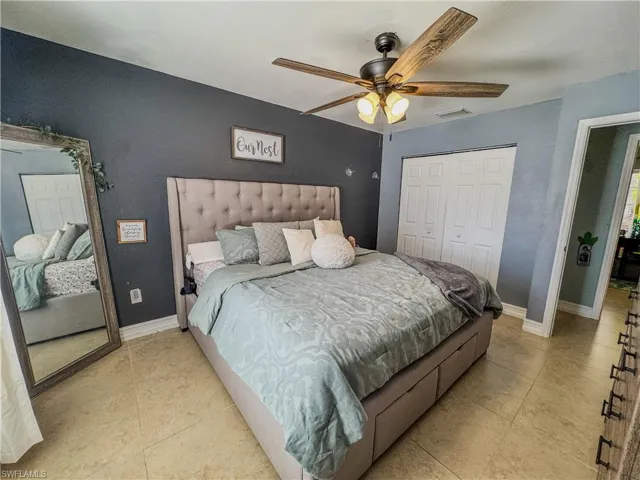Bedroom with light tile patterned floors, a closet, ceiling fan, and baseboards