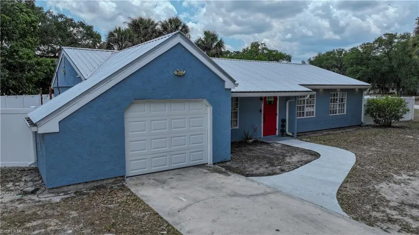 Single story home with concrete driveway, stucco siding, metal roof, and a garage