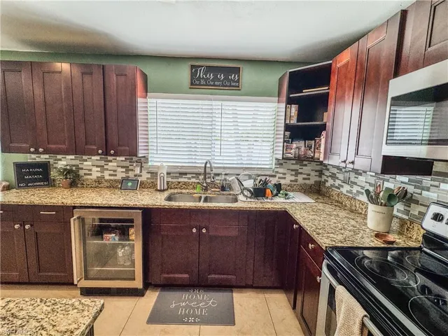 Kitchen with appliances with stainless steel finishes, beverage cooler, a sink, and tasteful backsplash