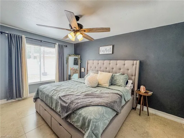Bedroom featuring baseboards, a textured ceiling, and a ceiling fan