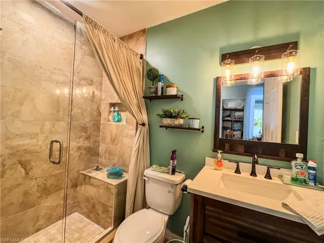 Full bathroom with a shower stall, toilet, and vanity