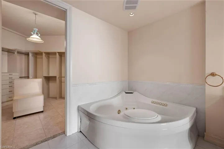 Full bath featuring a whirlpool tub, double vanity, and a sink