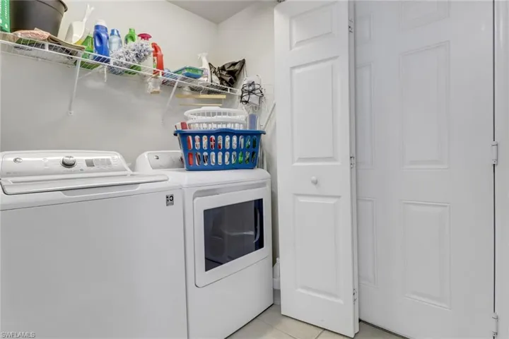 Laundry room with light tile patterned floors and washing machine and clothes dryer