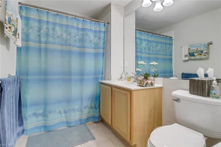 Full bathroom featuring light tile patterned floors, a shower with curtain, and vanity