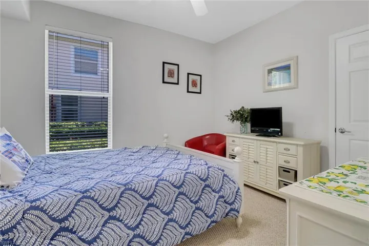 Bedroom featuring light colored carpet, ceiling fan, and multiple windows