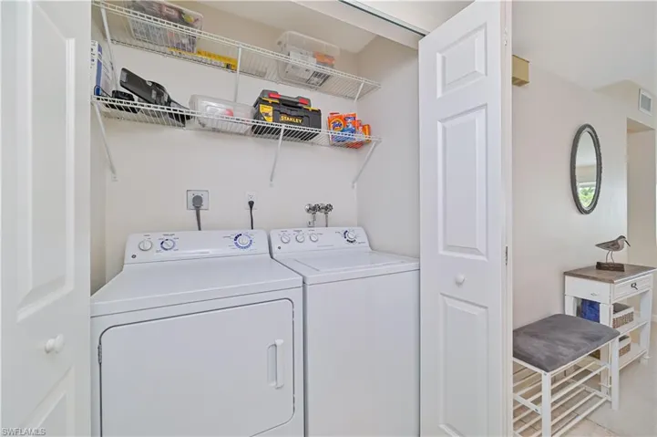 Dedicated laundry area featuring a washer and dryer, convenient wire shelving, and bi-fold panel doors
