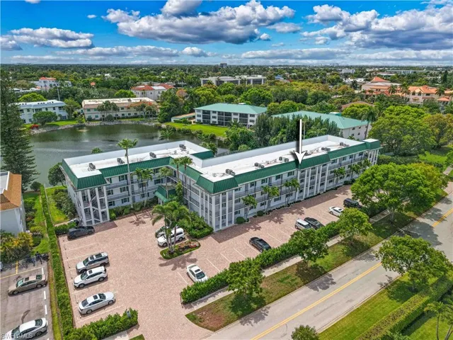 Multi-story residential building featuring a green metal roof and white exterior facade
