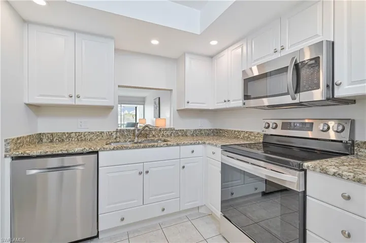 Kitchen featuring white cabinetry, speckled countertops, a stainless steel dishwasher, a stainless steel range with an overhead microwave, and recessed lighting
