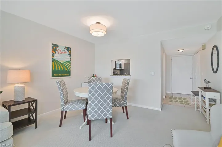Open-concept dining area featuring light-toned carpeting and a pass-through kitchen window
