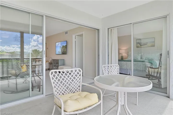 Private balcony with textured flooring, a glass-top table, and direct access to interior spaces through large sliding glass doors