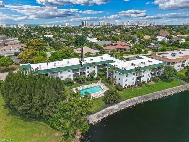 Waterfront condominium building with a green roof, private balconies, and a swimming pool