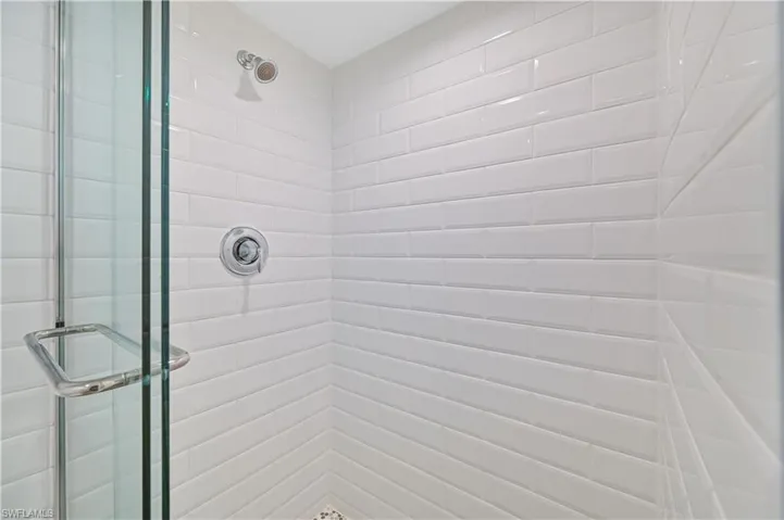White subway tile shower enclosure with chrome fixtures and clear glass door