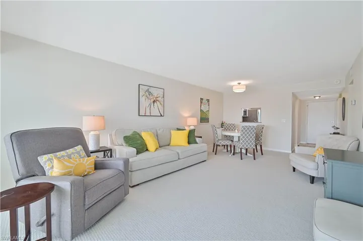 Open-concept living area with light-colored walls and plush carpeting throughout