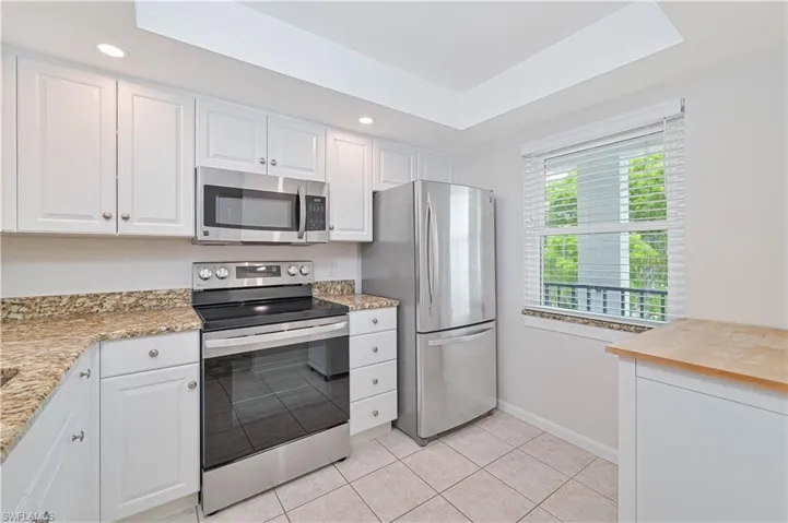 Kitchen featuring white cabinetry, stainless steel appliances, speckled stone countertops, and tile flooring