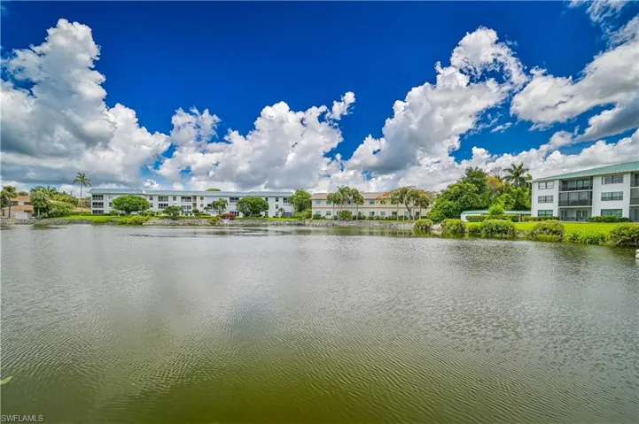 Waterfront property featuring multi-story buildings with balconies, surrounded by lush green landscaping and mature palm trees