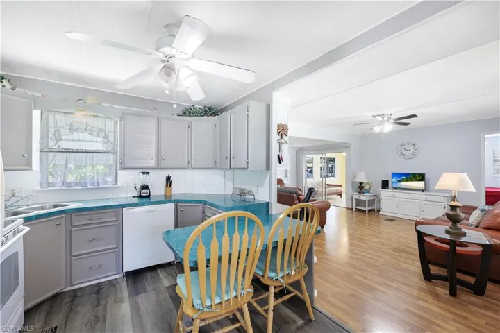 Kitchen with white appliances, ceiling fan, backsplash, open floor plan, and dark wood finished floors