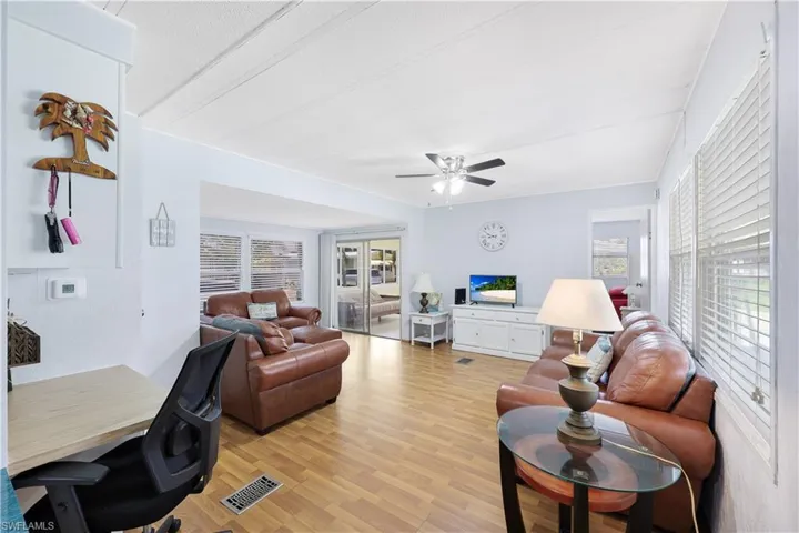 Living room with light wood-style flooring, plenty of natural light, ceiling fan, and a desk