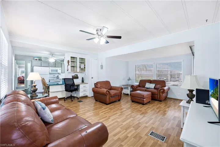 Living room with light wood-style flooring, ceiling fan, and built in study area