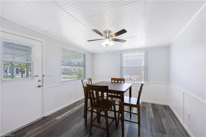 Dining room featuring dark wood-style floors, wainscoting, plenty of natural light, a ceiling fan, and ornamental molding