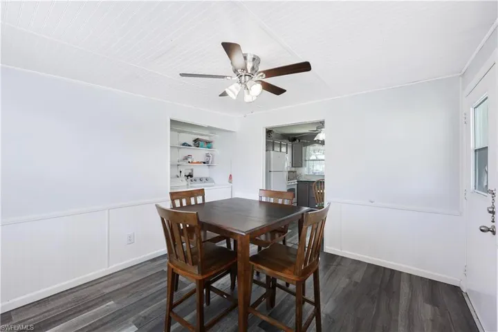 Dining space with wainscoting, dark wood finished floors, washer and clothes dryer, and a ceiling fan
