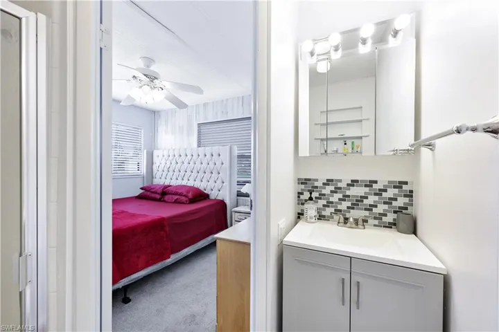 Bathroom with connected bathroom, vanity, decorative backsplash, ceiling fan, and carpet flooring