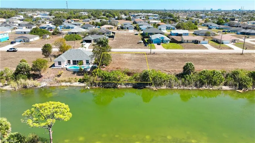 Aerial perspective of suburban area with property parcel outlined and a large body of water