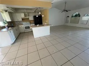 Kitchen featuring white cabinets, ceiling fan, open floor plan, light countertops, and lofted ceiling