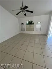 Empty room featuring light tile patterned flooring, a ceiling fan, and lofted ceiling