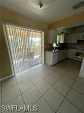 Kitchen featuring white cabinetry, light tile patterned flooring, stainless steel range, and dark countertops