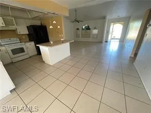 Kitchen featuring open floor plan, white stove, ceiling fan, and light tile patterned floors
