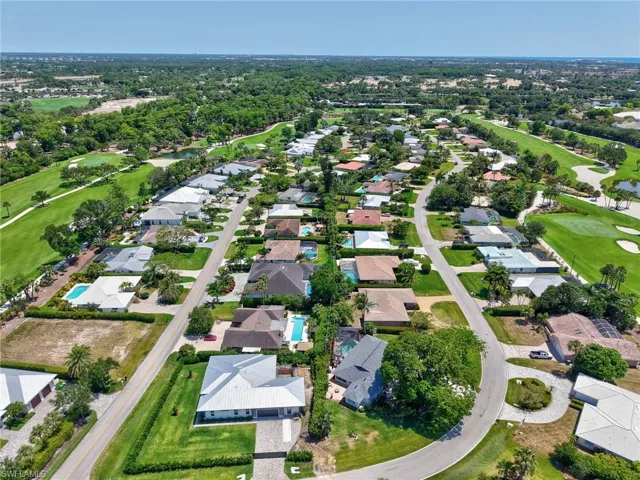 Aerial view of property and surrounding area with nearby suburban area, a local golf course, and a large body of water