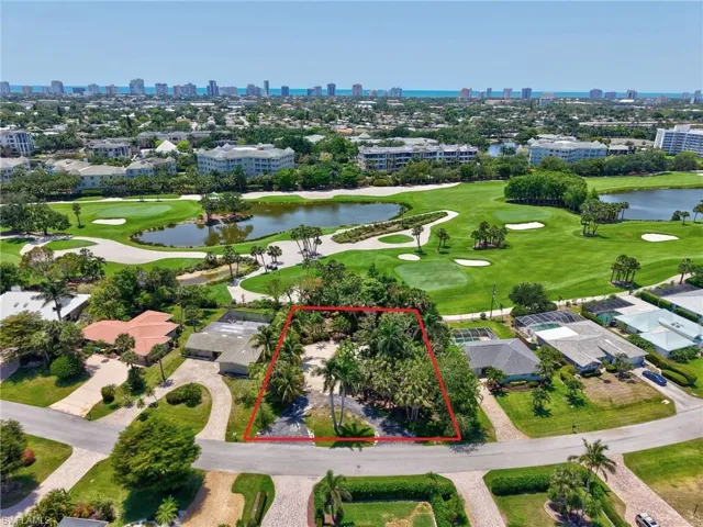 Aerial overview of property's location featuring a view of skyline, a nearby body of water, a golf course, and property parcel outlined