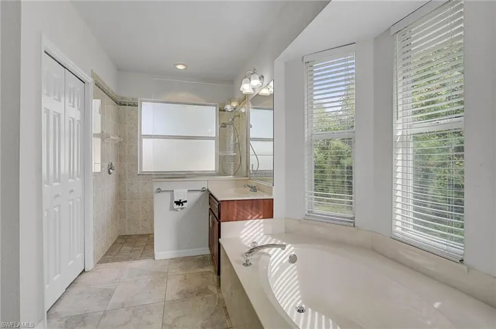 Bathroom featuring vanity, walk in shower, plenty of natural light, and a bath