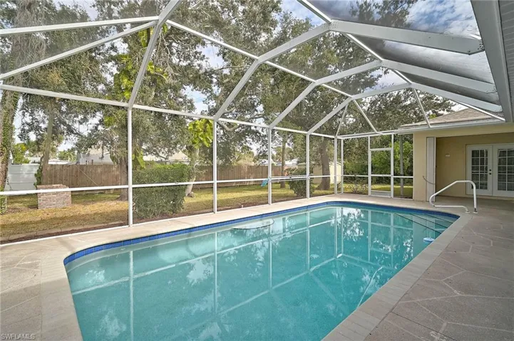 View of swimming pool featuring a lanai,  a patio, and french doors