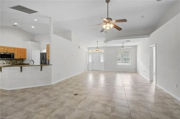 Unfurnished Family room and bonus room featuring a ceiling fan, light tile patterned floors, and high vaulted ceiling