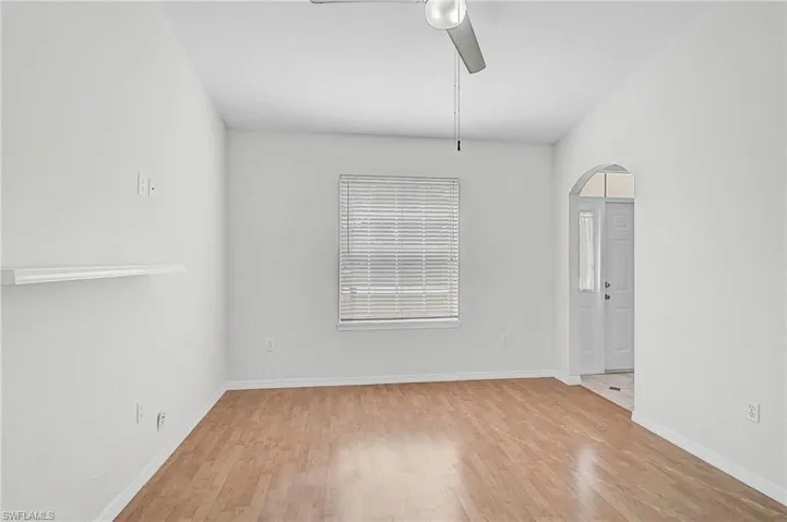 Unfurnished room with light wood-style floors, ceiling fan, and arched walkways