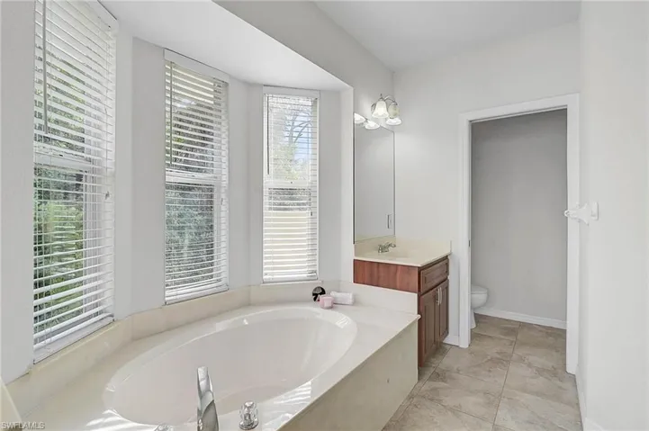 Bathroom featuring a garden tub, vanity, and light tile patterned floors